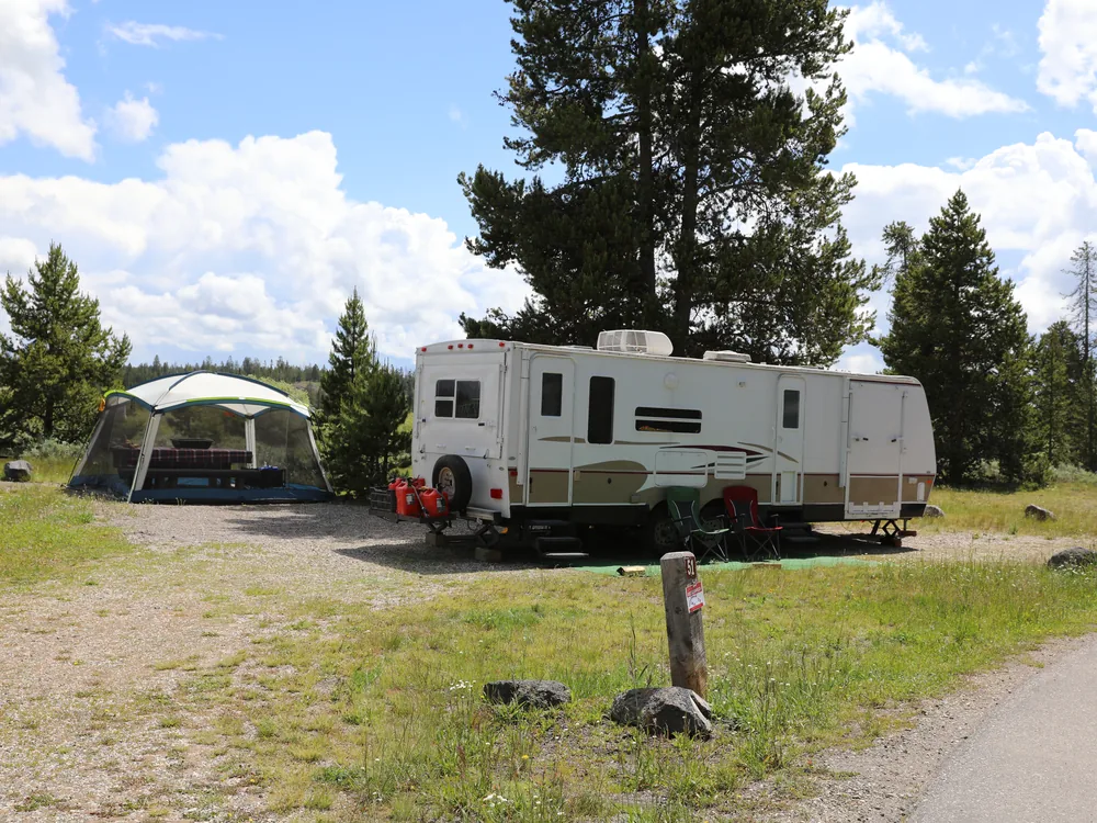An RV trailer and screen tent at a national-forest campground site